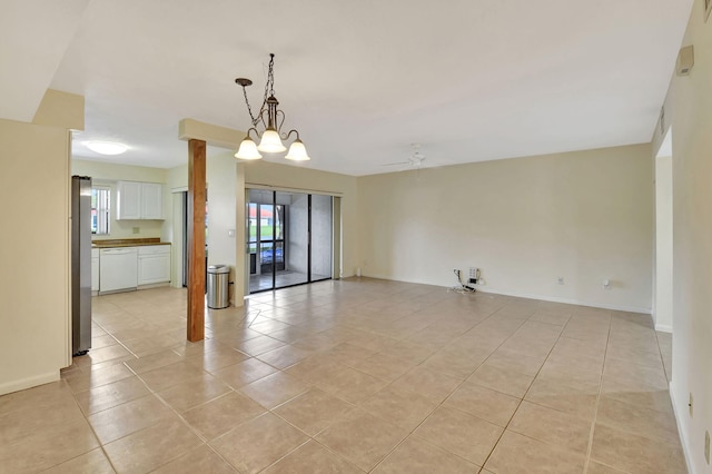 spare room featuring light tile patterned floors, baseboards, and ceiling fan with notable chandelier