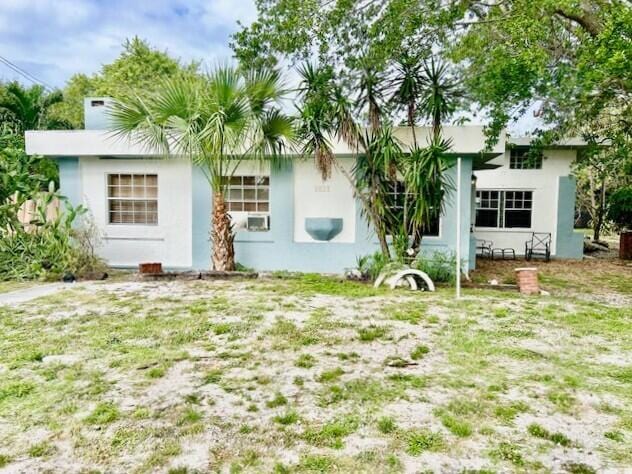 back of house with a lawn and stucco siding