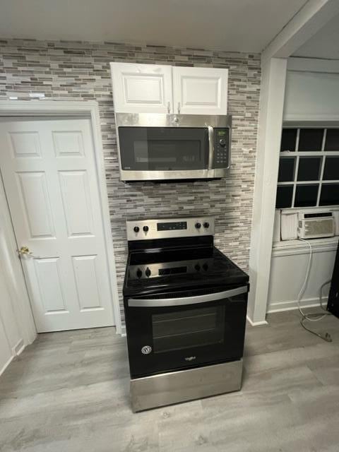 kitchen with stainless steel appliances, cooling unit, white cabinetry, and light wood finished floors