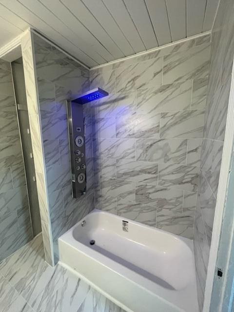 full bath featuring shower / washtub combination and marble finish floor