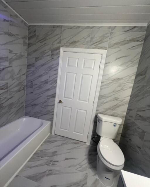 bathroom featuring marble finish floor, tub / shower combination, tile walls, and toilet