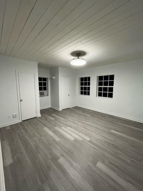 unfurnished room with wooden ceiling, dark wood-style floors, and baseboards