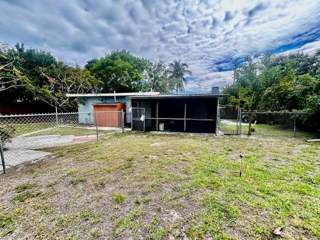 back of property featuring a yard, a fenced backyard, and a sunroom