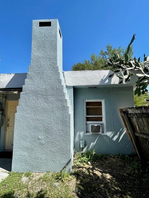 view of property exterior with a chimney, cooling unit, and stucco siding