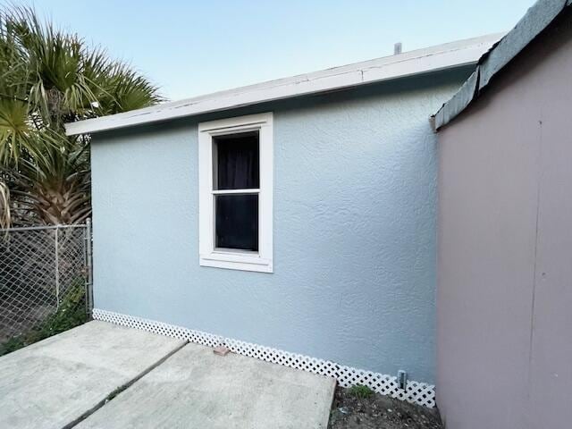 view of side of home featuring fence and stucco siding