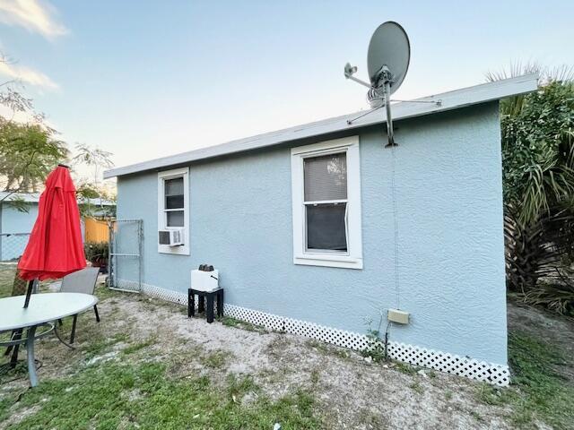 view of side of home with cooling unit, fence, and stucco siding