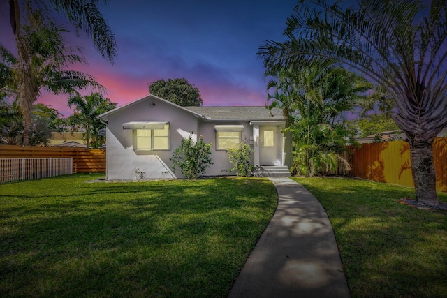 view of front of property with fence private yard, a yard, and stucco siding