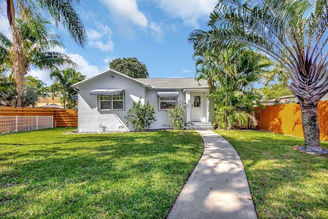 view of front of property featuring a front yard, a fenced backyard, and stucco siding