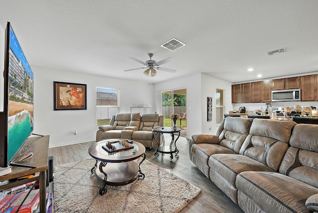 living area featuring a textured ceiling, visible vents, wood finished floors, and recessed lighting