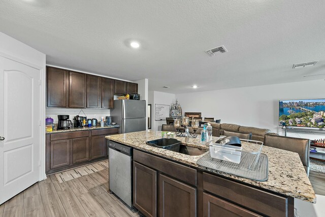 kitchen with appliances with stainless steel finishes, light wood-type flooring, visible vents, and a sink