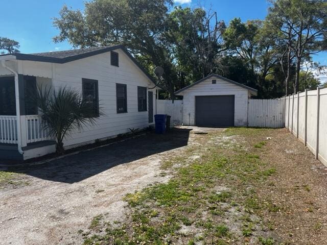 view of side of home with dirt driveway, an outbuilding, a fenced backyard, and a garage