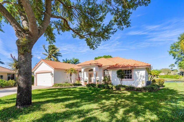 mediterranean / spanish house with stucco siding, a front lawn, concrete driveway, and an attached garage