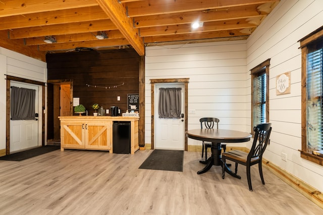 kitchen with wood walls, beamed ceiling, wood counters, and light wood-style flooring