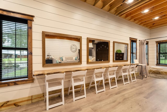 bar with a healthy amount of sunlight, wooden walls, and wood finished floors