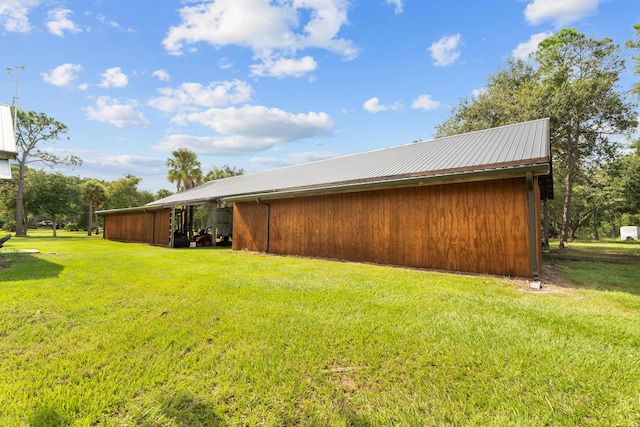 view of home's exterior featuring an outdoor structure, metal roof, a lawn, and an outbuilding