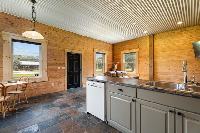 kitchen featuring decorative light fixtures, dark countertops, white cabinetry, white dishwasher, and a sink