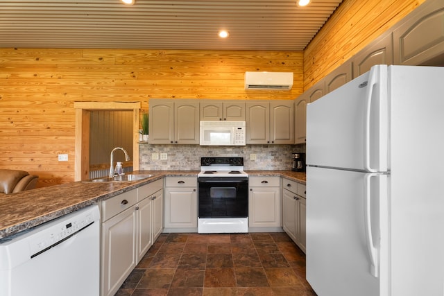 kitchen featuring white appliances, decorative backsplash, a wall unit AC, a peninsula, and a sink