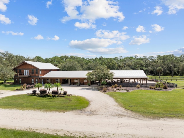 view of community featuring a rural view, a lawn, and driveway