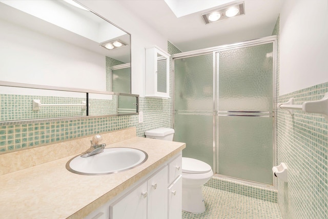 bathroom with toilet, tile patterned floors, vanity, a shower stall, and tile walls