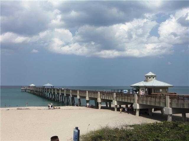 view of dock featuring a pier, a view of the beach, and a water view