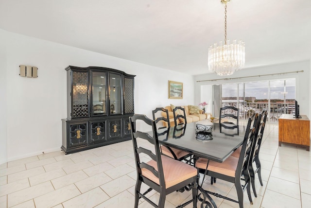 dining area with a chandelier, light tile patterned flooring, and baseboards