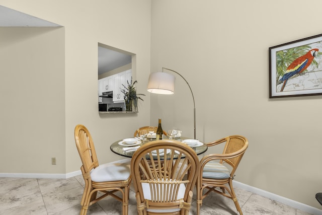 dining space featuring light tile patterned floors and baseboards