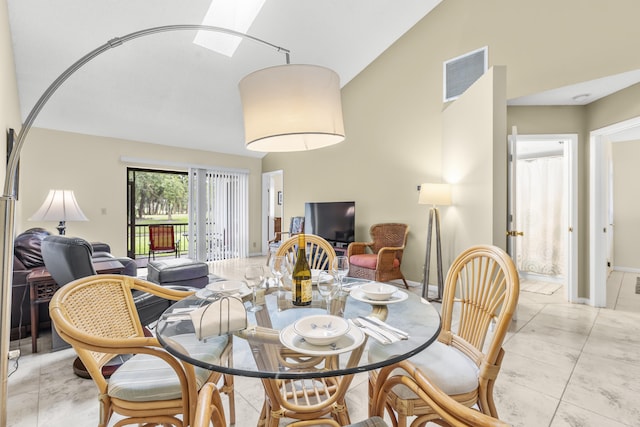 dining space featuring high vaulted ceiling, a skylight, visible vents, and baseboards