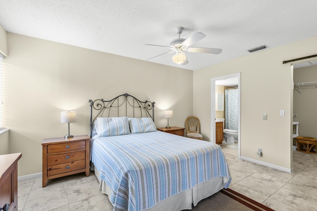 bedroom with a barn door, visible vents, a walk in closet, and baseboards