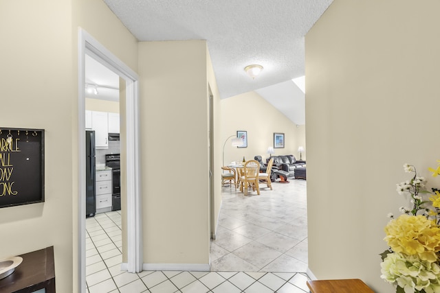 corridor featuring lofted ceiling, light tile patterned floors, and a textured ceiling