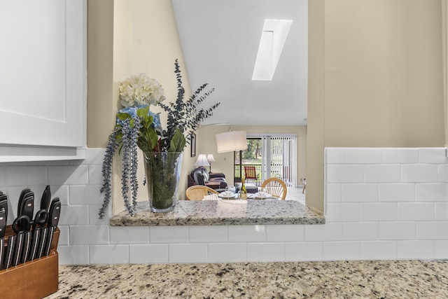 room details featuring light stone counters, a skylight, and white cabinets