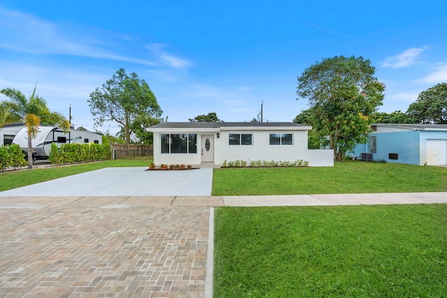 ranch-style home with driveway, fence, central air condition unit, a front lawn, and stucco siding