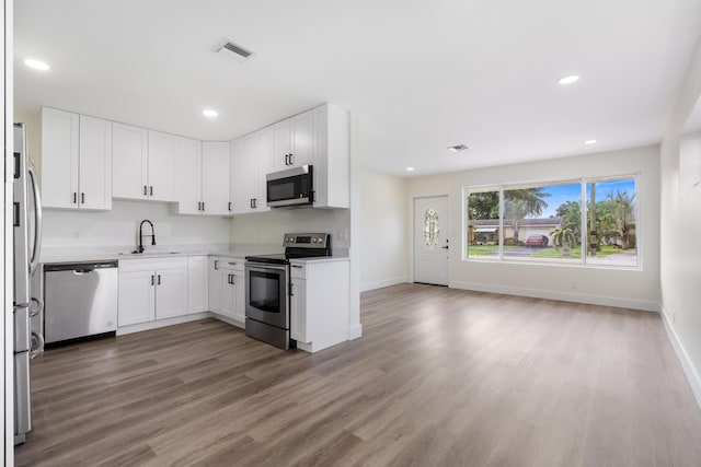 kitchen featuring stainless steel appliances, wood finished floors, visible vents, white cabinetry, and light countertops