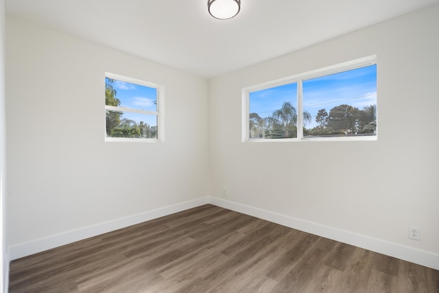 spare room with baseboards, dark wood finished floors, and a wealth of natural light