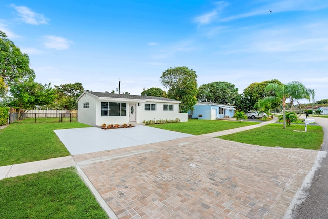 view of front facade featuring a front yard, decorative driveway, fence, and stucco siding