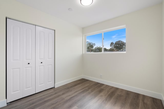 unfurnished bedroom with a closet, wood finished floors, and baseboards