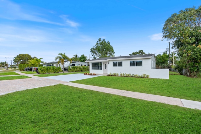 ranch-style house with driveway, a front lawn, and stucco siding