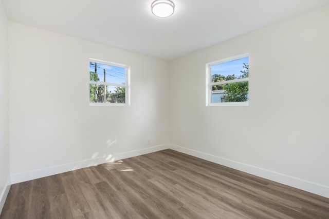 unfurnished room featuring a wealth of natural light, baseboards, and wood finished floors