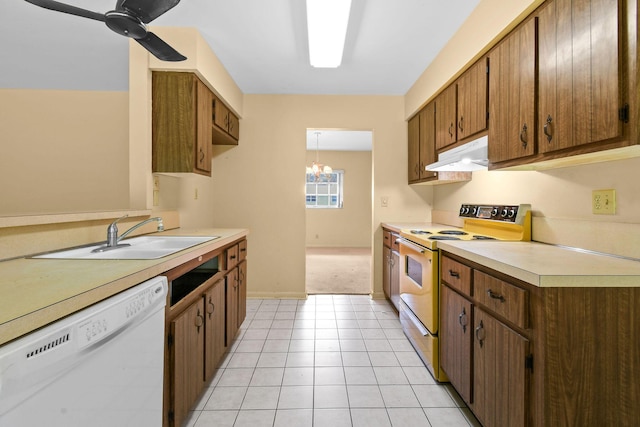 kitchen with under cabinet range hood, ceiling fan with notable chandelier, white appliances, a sink, and light countertops