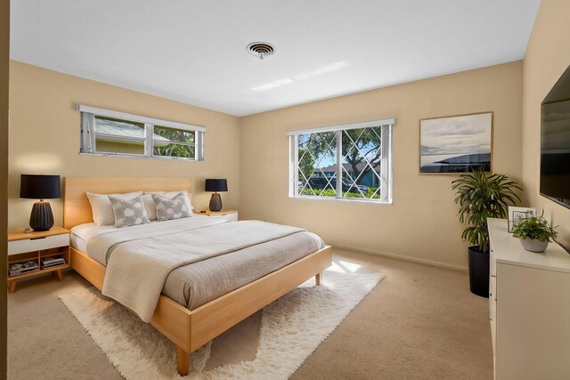 bedroom featuring visible vents, light carpet, baseboards, and multiple windows