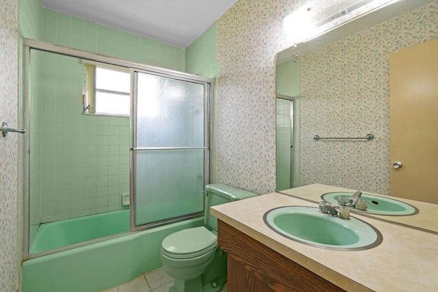 bathroom with toilet, shower / bath combination with glass door, vanity, tile patterned floors, and wallpapered walls