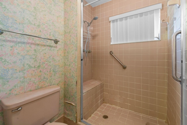 bathroom with a shower stall, toilet, and wallpapered walls