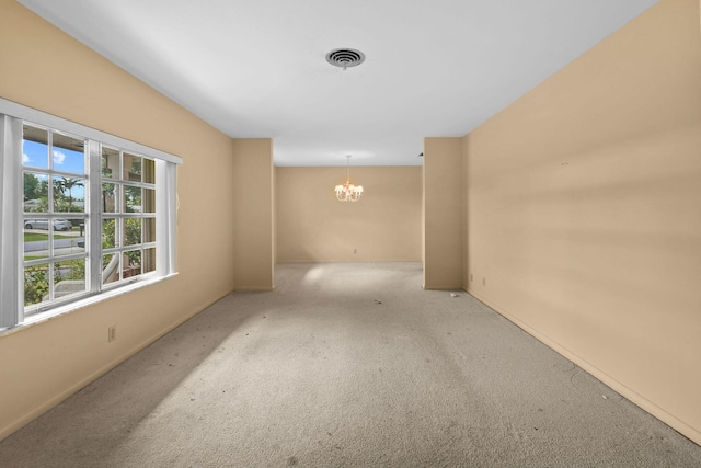 carpeted empty room featuring an inviting chandelier, baseboards, and visible vents