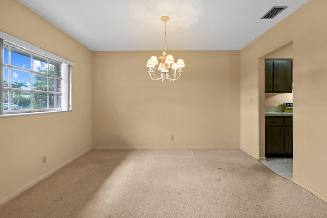 spare room with baseboards, light colored carpet, visible vents, and an inviting chandelier