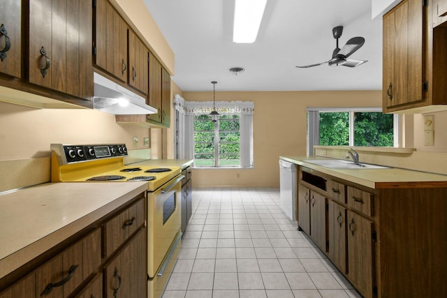 kitchen with white appliances, light tile patterned floors, light countertops, under cabinet range hood, and a sink