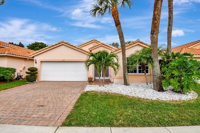 view of front of property with a garage, a tile roof, decorative driveway, and stucco siding