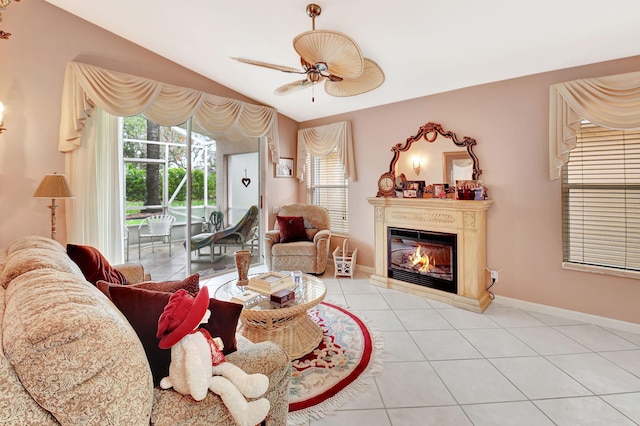 living room featuring lofted ceiling, light tile patterned floors, plenty of natural light, and a glass covered fireplace