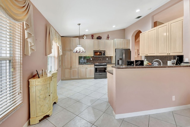 kitchen featuring stainless steel appliances, lofted ceiling, dark stone counters, and light tile patterned floors