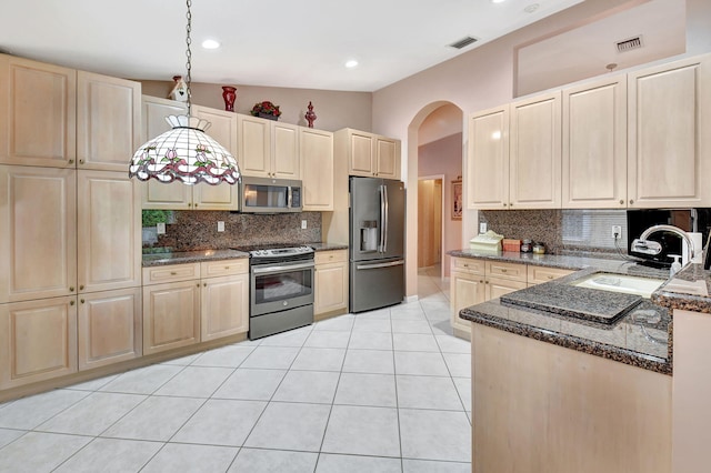 kitchen featuring light tile patterned floors, arched walkways, stainless steel appliances, a sink, and visible vents