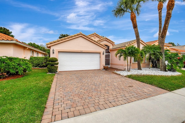 mediterranean / spanish-style home featuring a tiled roof, an attached garage, decorative driveway, a front lawn, and stucco siding