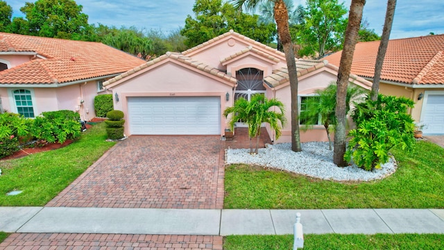 mediterranean / spanish house with decorative driveway, a tiled roof, an attached garage, and stucco siding